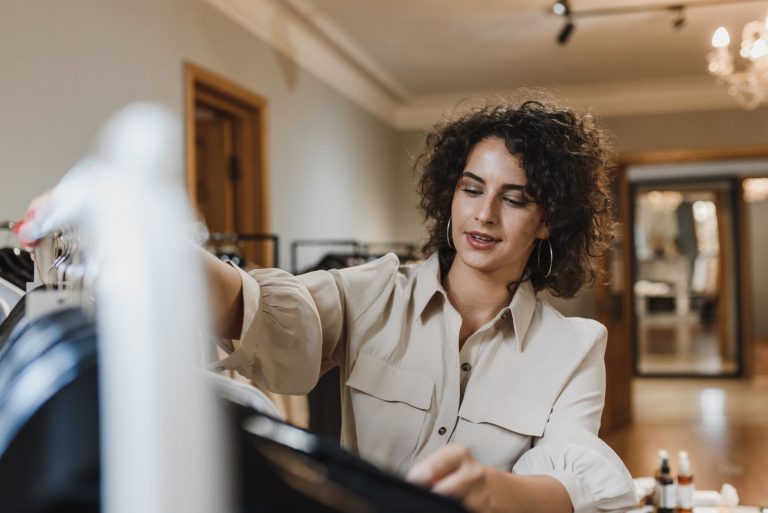 A woman browses clothes in a stylish indoor boutique, focusing on wardrobe choices.