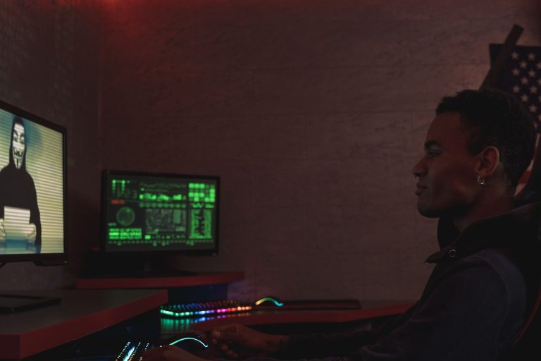 A cybersecurity professional monitors data systems in a dark room, emphasizing protection and vigilance.