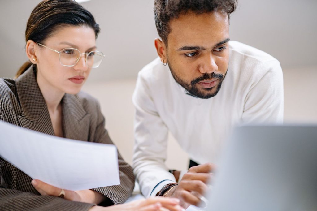 Two colleagues engaged in teamwork, analyzing documents in a modern office environment.