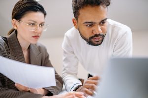 Two colleagues engaged in teamwork, analyzing documents in a modern office environment.